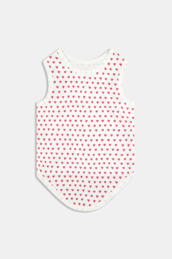 A brown poodle sits on a white background wearing Roller Rabbit's Hearts Dog Pajamas, adorable Pima Cotton pet PJs featuring small pink heart patterns for perfect matching dog pajamas.