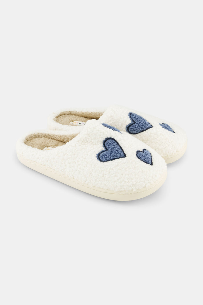 Roller Rabbit Hearts Fuzzy Slippers feature an open-back design, cozy shearling lining, blue heart details on top, and a durable rubber sole for comfort.
