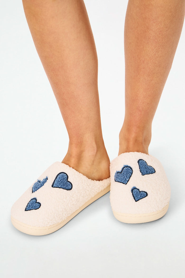 Roller Rabbit Hearts Fuzzy Slippers feature an open-back design, cozy shearling lining, blue heart details on top, and a durable rubber sole for comfort.