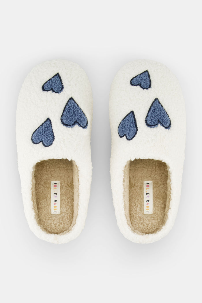Roller Rabbit Hearts Fuzzy Slippers feature an open-back design, cozy shearling lining, blue heart details on top, and a durable rubber sole for comfort.