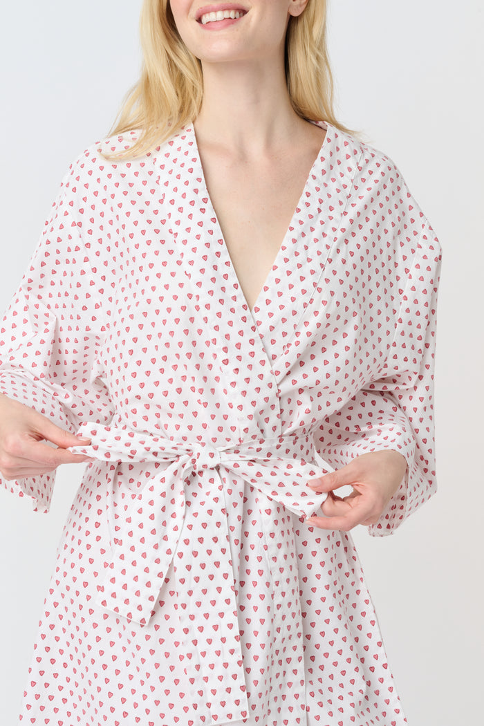 A woman stands barefoot, smiling in a Roller Rabbit Hearts Kimono with a matching belt, set against a plain white background.