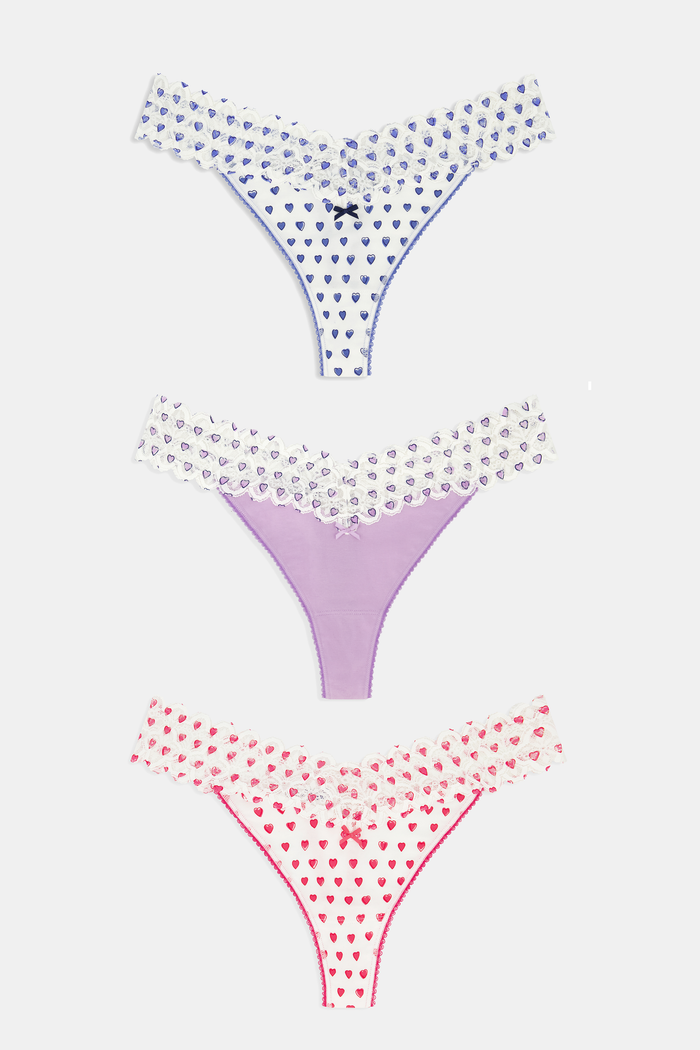 The Roller Rabbit Hearts Lace Thong 3 Pack features three thongs displayed vertically: blue hearts on top, solid lavender in the middle, and red hearts on the bottom, each with a center bow for a comfy and cute look.