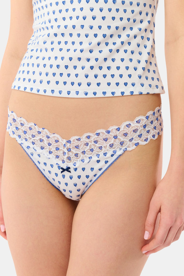 The Roller Rabbit Hearts Lace Thong 3 Pack features three thongs displayed vertically: blue hearts on top, solid lavender in the middle, and red hearts on the bottom, each with a center bow for a comfy and cute look.