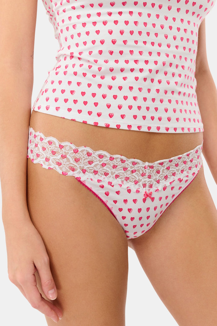 The Roller Rabbit Hearts Lace Thong 3 Pack features three thongs displayed vertically: blue hearts on top, solid lavender in the middle, and red hearts on the bottom, each with a center bow for a comfy and cute look.