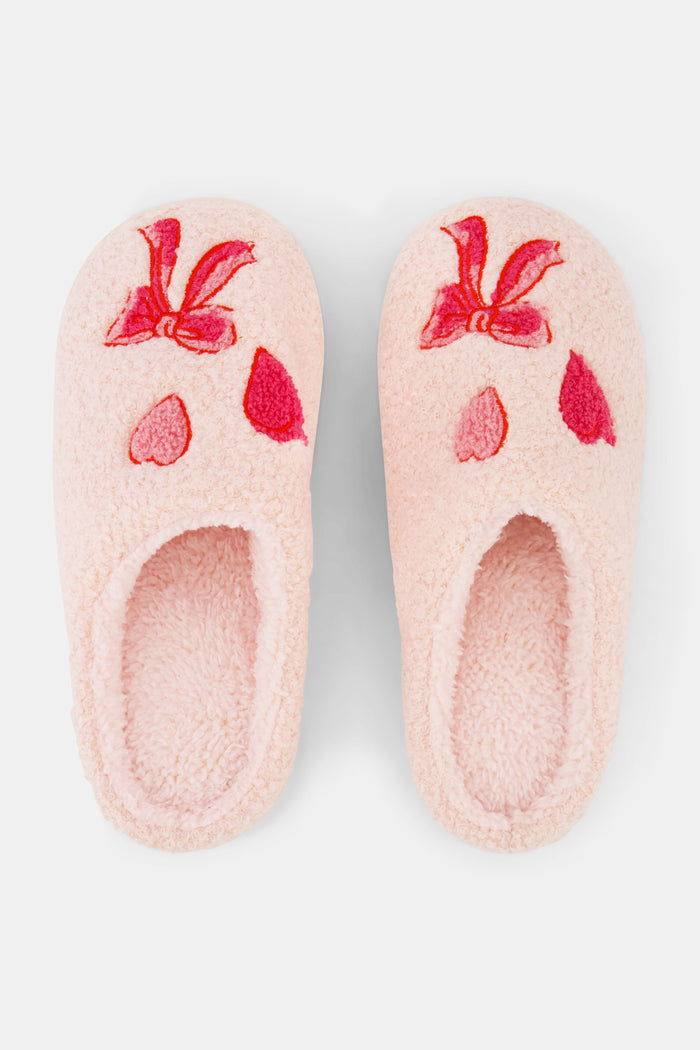The Roller Rabbit Hearts N' Bows Fuzzy Slipper, shown from above on a white background, features pink fuzzy material with a red and pink floral embroidery and a durable rubber sole for comfort and support.