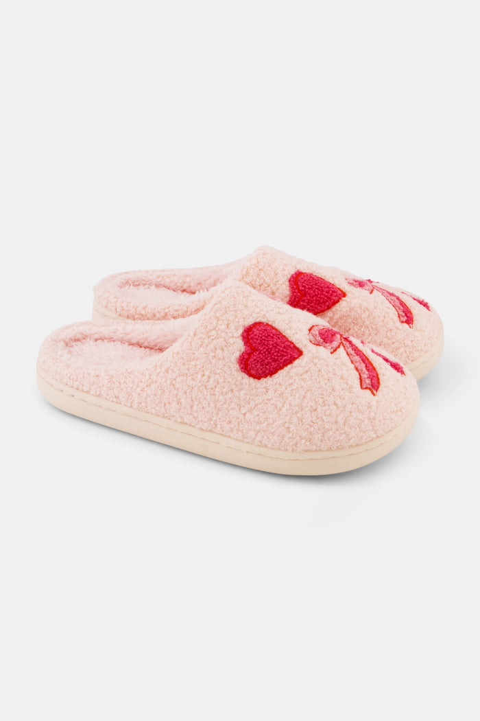 The Roller Rabbit Hearts N' Bows Fuzzy Slipper, shown from above on a white background, features pink fuzzy material with a red and pink floral embroidery and a durable rubber sole for comfort and support.
