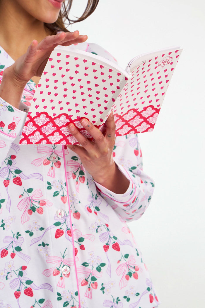 The Hearts Notebook by Roller Rabbit features a white cover with small red and pink hearts, a scalloped red and white floral border at the bottom, and a “RR” logo—perfect for pairing with your favorite lined notebook.