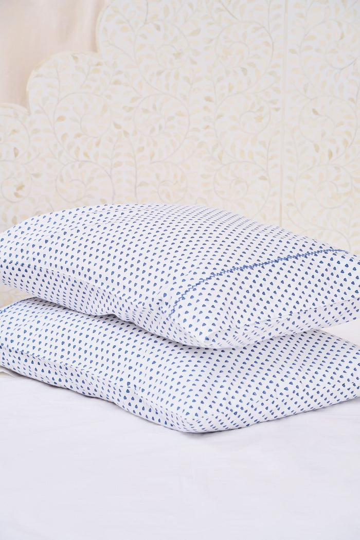The Roller Rabbit Hearts Pillowcase Set features two white 100 cotton pillowcases with small blue leaf patterns, offering breathable comfort and style to your space. Shown stacked on a white surface against a cream-colored background.