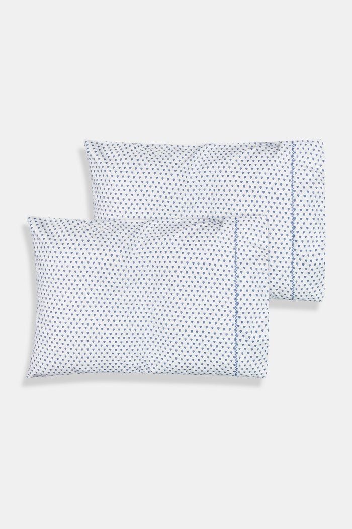 The Roller Rabbit Hearts Pillowcase Set features two white 100 cotton pillowcases with small blue leaf patterns, offering breathable comfort and style to your space. Shown stacked on a white surface against a cream-colored background.