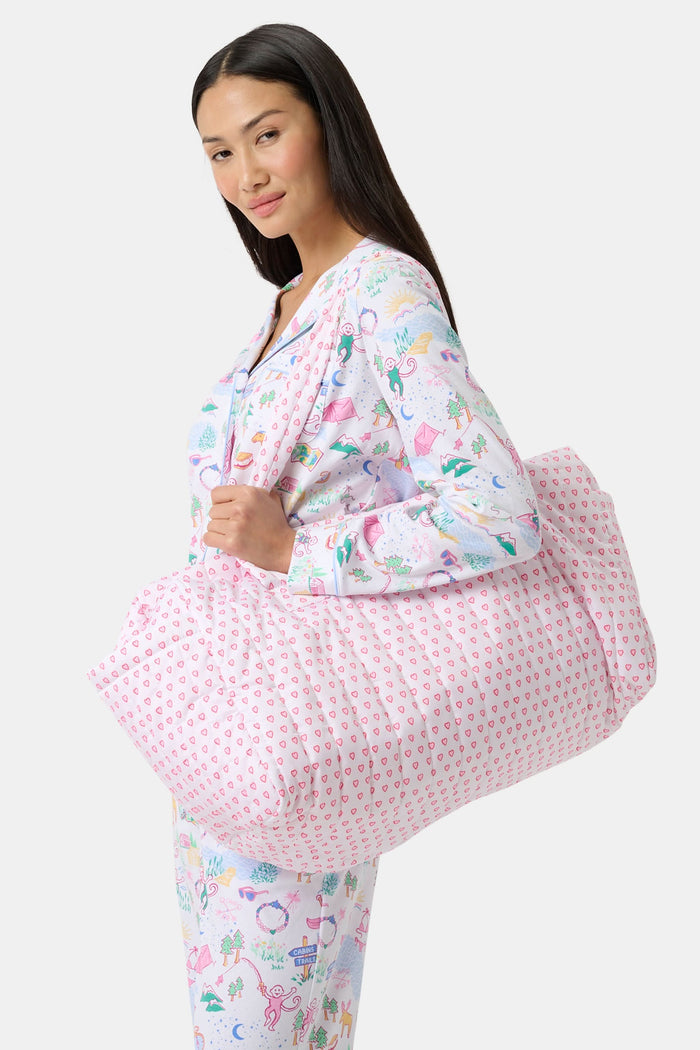The Hearts Quilted Weekender by Roller Rabbit is a pink and white canvas bag with two handles, featuring a repeating pattern of small pink hearts on a white background.