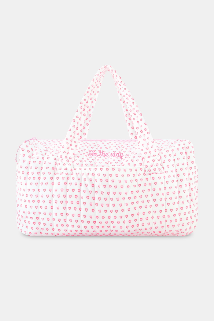 The Hearts Quilted Weekender by Roller Rabbit is a pink and white canvas bag with two handles, featuring a repeating pattern of small pink hearts on a white background.