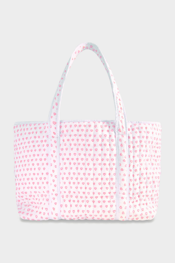 The Roller Rabbit Hearts Terry Beach Tote is a large quilted bag with two handles, featuring a white background and pink heart pattern—ideal for the beach or carrying your daily essentials.