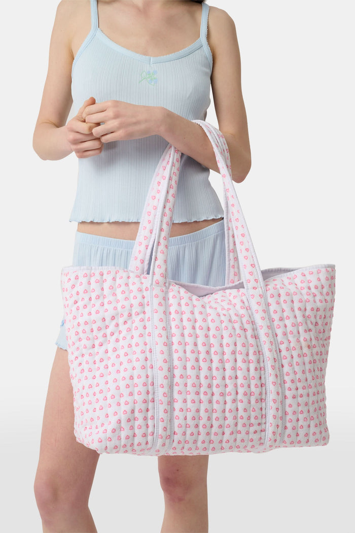 The Roller Rabbit Hearts Terry Beach Tote is a large quilted bag with two handles, featuring a white background and pink heart pattern—ideal for the beach or carrying your daily essentials.