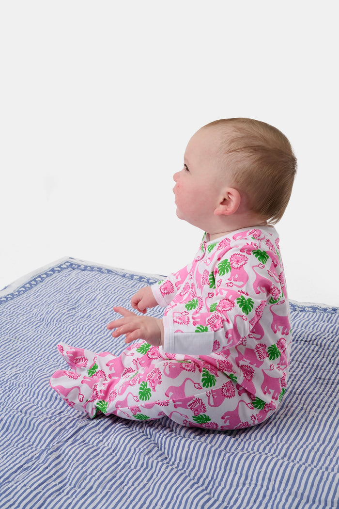 A smiling baby with light skin and short hair sits on a blue and white striped blanket wearing the Roller Rabbit Infant Leo The Lion Zipper Footie, made from soft Pima cotton with a convenient two-way zipper for easy dressing.