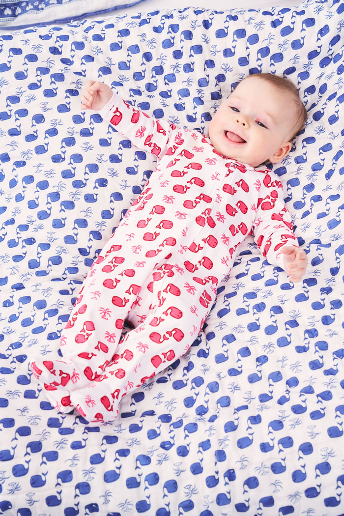 The Roller Rabbit Infant Moby Zipper Footie is a white, long-sleeve, 100 Pima cotton onesie with covered feet. It features a red Santa Claus and palm tree pattern and a front zipper from neck to foot.