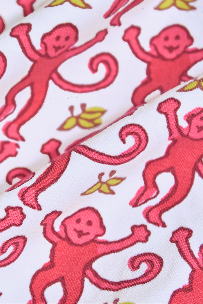 The Roller Rabbit Infant Monkey Zipper Footie features a playful pink monkey pattern with yellow accents, long sleeves and legs, and is crafted from premium cotton. It’s shown laid flat on a plain background.