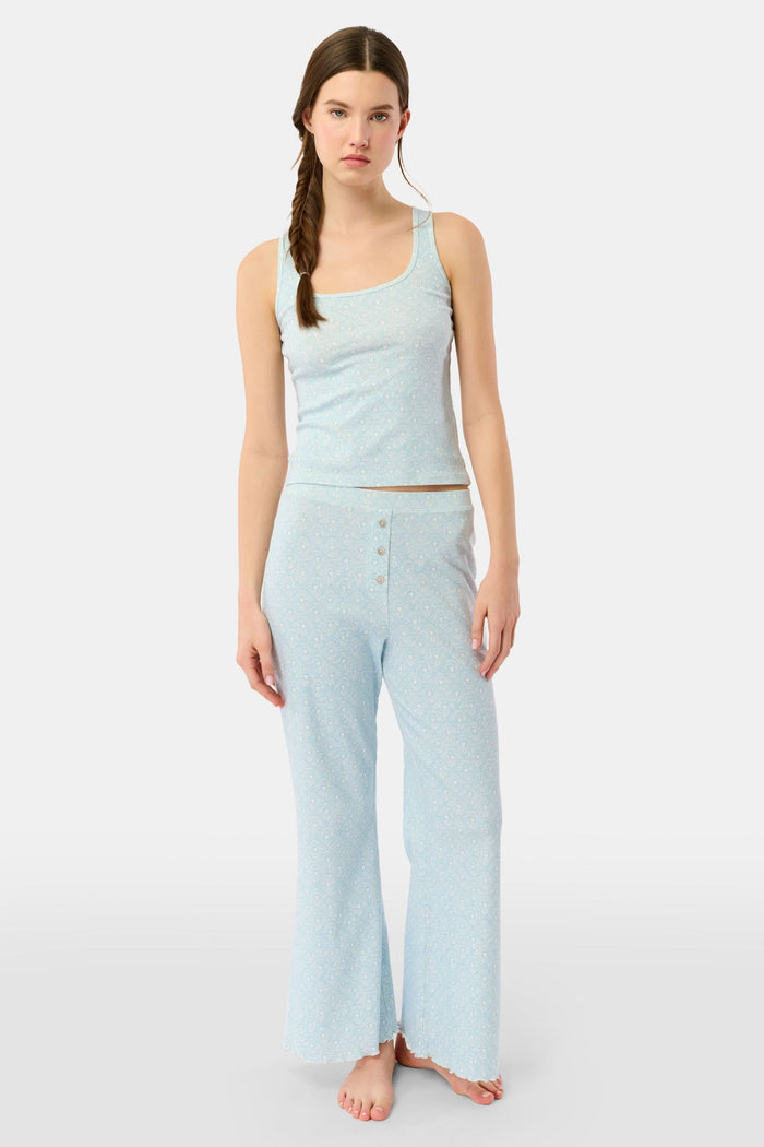 A young woman with long brown hair in a side braid models the Jemina Hearts Pointelle Astor Tank by Roller Rabbit, a pastel blue top, against a plain white background.