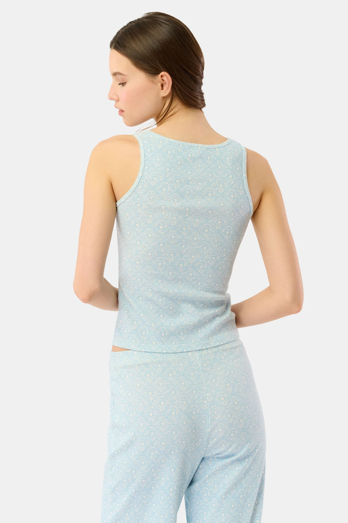A young woman with long brown hair in a side braid models the Jemina Hearts Pointelle Astor Tank by Roller Rabbit, a pastel blue top, against a plain white background.