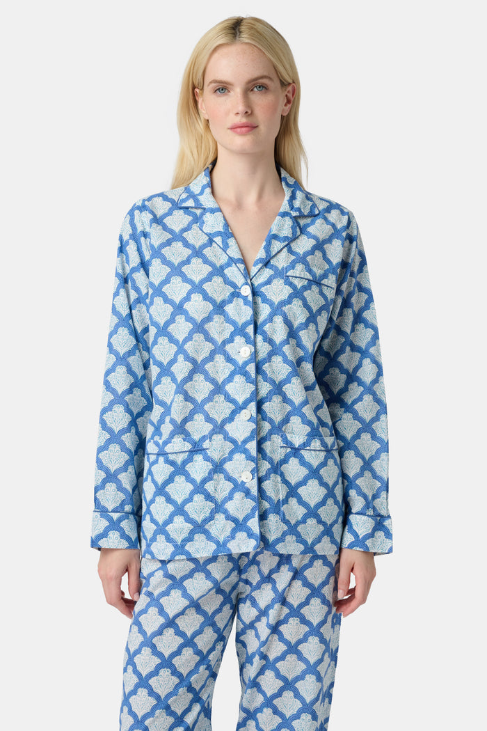A woman stands barefoot against a plain white background wearing the Roller Rabbit Jemina Loungewear set, featuring a blue and white medallion print button-up long-sleeve top with matching pants.