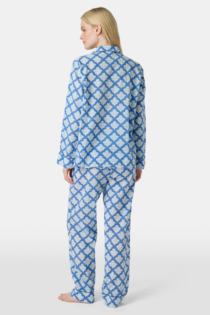 A woman stands barefoot against a plain white background wearing the Roller Rabbit Jemina Loungewear set, featuring a blue and white medallion print button-up long-sleeve top with matching pants.