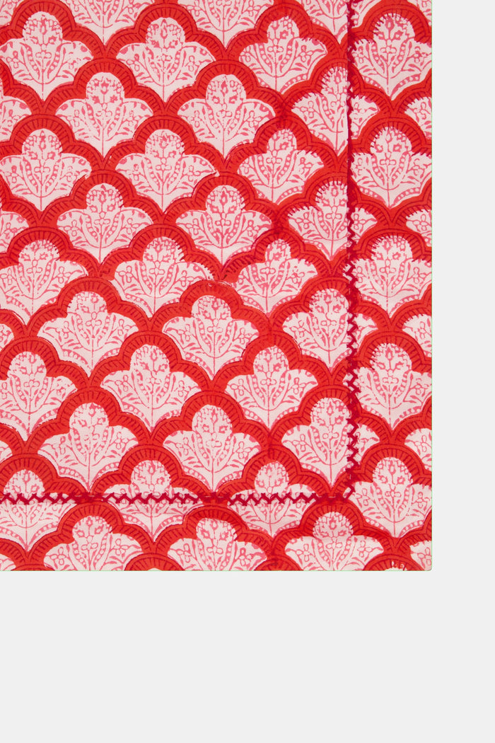 Two stacked Roller Rabbit Jemina Pillowcase Set pillowcases in a red and white print rest on a matching 100 cotton bedsheet, set against a white decorative background.