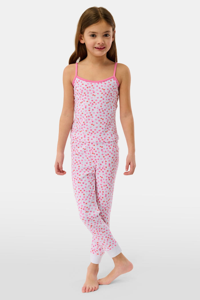 A young girl with long brown hair wears the Roller Rabbit Kids Bouquet Campbell Set, a pink and white pajama set with a floral print. She stands barefoot, smiling, against a plain light background with one foot slightly raised.