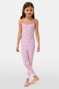 A young girl with long brown hair wears the Roller Rabbit Kids Bouquet Campbell Set, a pink and white pajama set with a floral print. She stands barefoot, smiling, against a plain light background with one foot slightly raised.