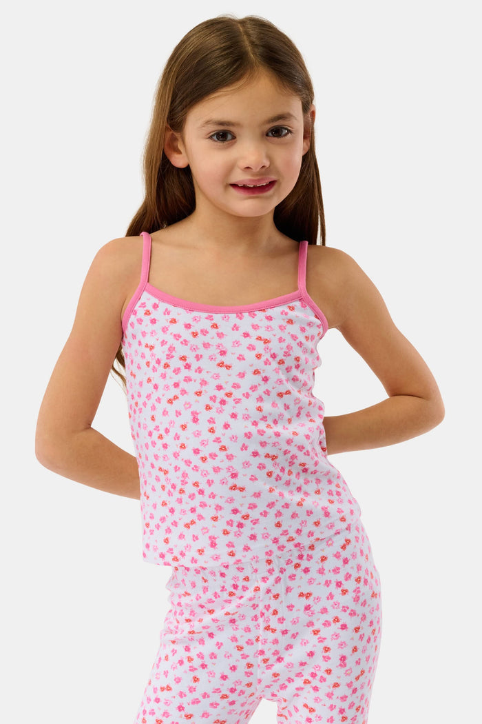 A young girl with long brown hair wears the Roller Rabbit Kids Bouquet Campbell Set, a pink and white pajama set with a floral print. She stands barefoot, smiling, against a plain light background with one foot slightly raised.