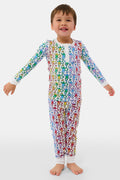 A young child stands barefoot and smiling, wearing Roller Rabbit Kids Disco Monkey Pajamas—crafted from soft 100 pima cotton with a playful monkey print on white—perfect for cozy kids sleepwear.