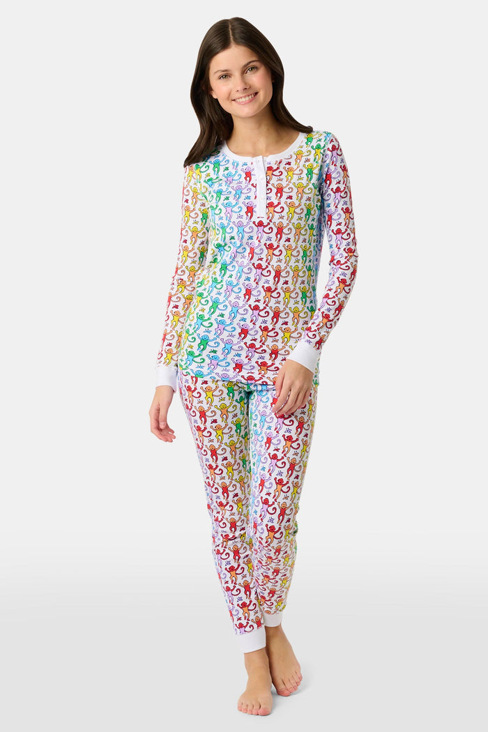 A young child stands barefoot and smiling, wearing Roller Rabbit Kids Disco Monkey Pajamas—crafted from soft 100 pima cotton with a playful monkey print on white—perfect for cozy kids sleepwear.