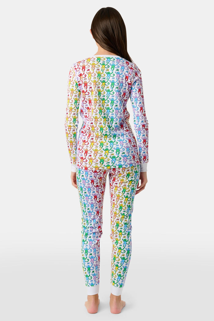 A young child stands barefoot and smiling, wearing Roller Rabbit Kids Disco Monkey Pajamas—crafted from soft 100 pima cotton with a playful monkey print on white—perfect for cozy kids sleepwear.