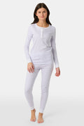 A girl stands barefoot in Roller Rabbit Kids Hearts Pajamas: a 100 cotton set with a fitted white long-sleeve top and purple heart-print pants with white cuffs, against a plain light background.