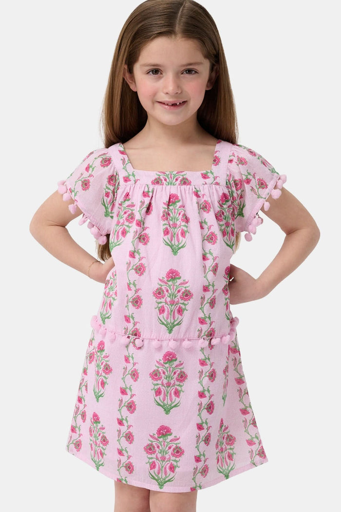 A young girl with long brown hair smiles, wearing the Roller Rabbit Kids Lily Stripe Oceana Dress. She stands with her hands on her hips against a plain light background.