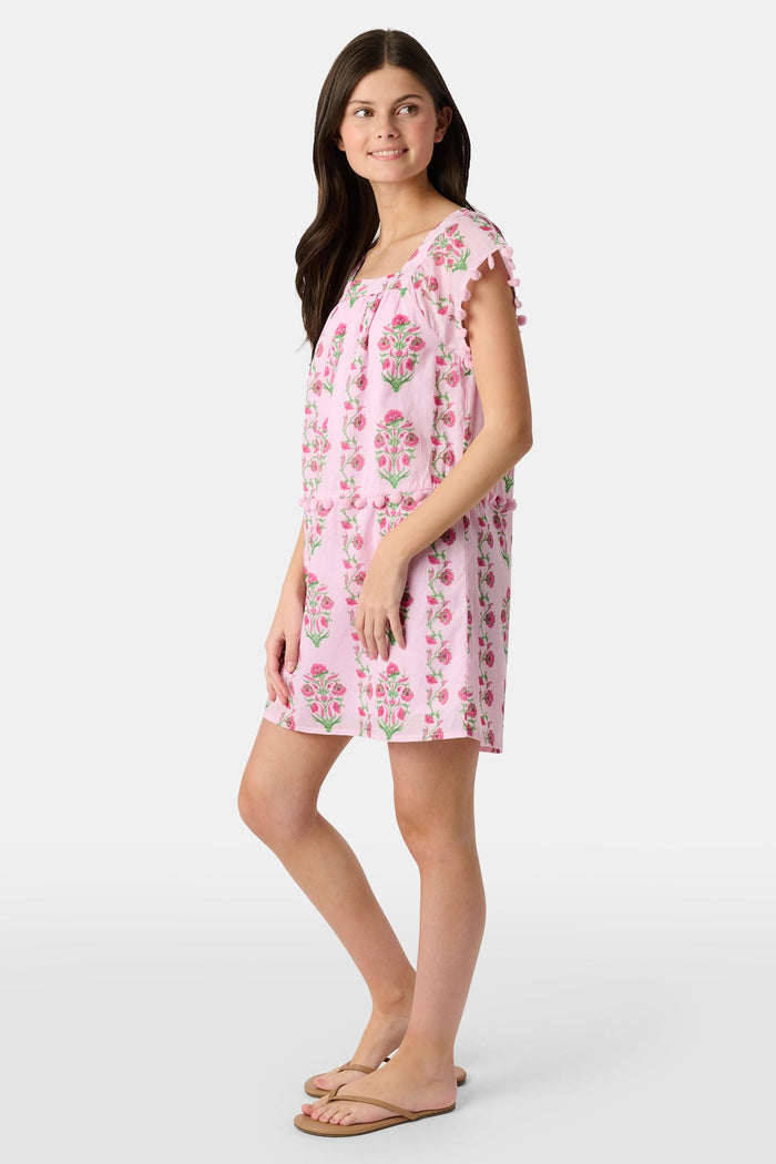 A young girl with long brown hair smiles, wearing the Roller Rabbit Kids Lily Stripe Oceana Dress. She stands with her hands on her hips against a plain light background.