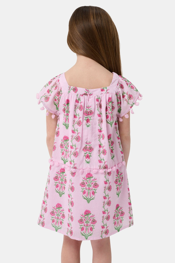 A young girl with long brown hair smiles, wearing the Roller Rabbit Kids Lily Stripe Oceana Dress. She stands with her hands on her hips against a plain light background.