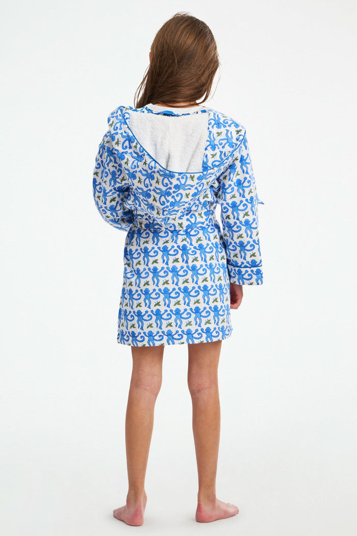 A young girl stands smiling in a Roller Rabbit Kids Monkey Cosmo Bathrobe over a matching shirt, against a plain white background.