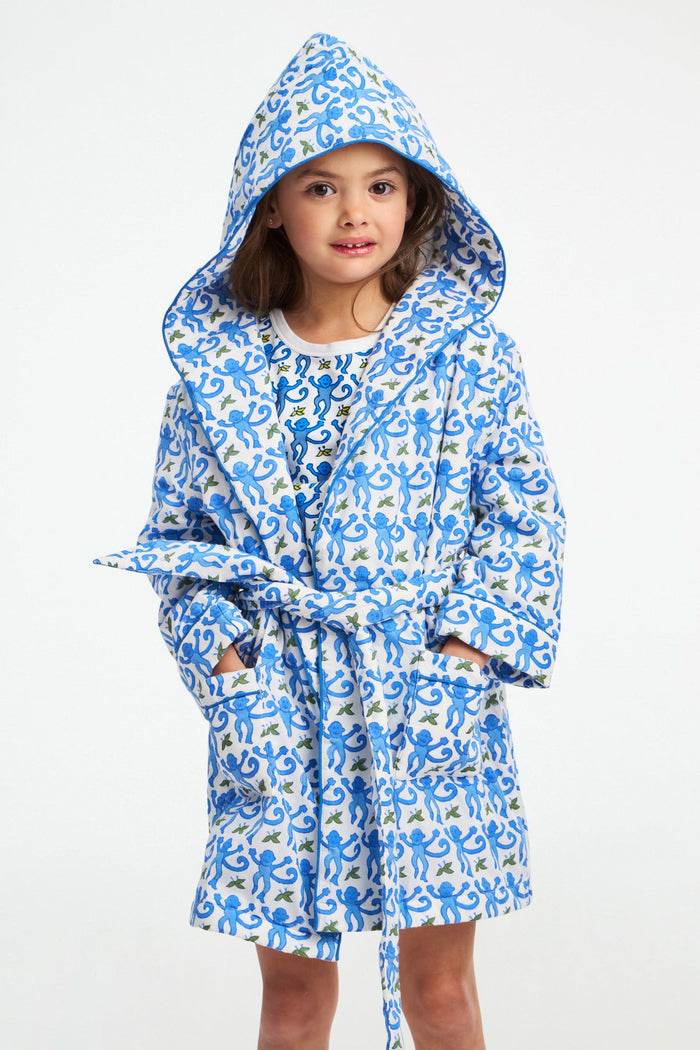 A young girl stands smiling in a Roller Rabbit Kids Monkey Cosmo Bathrobe over a matching shirt, against a plain white background.