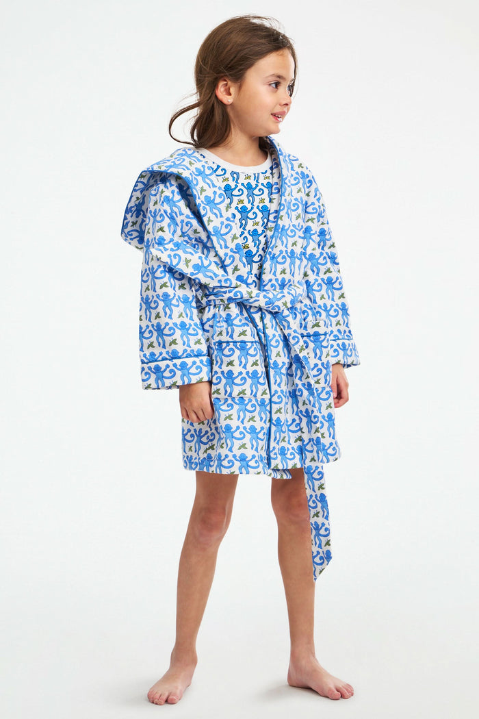 A young girl stands smiling in a Roller Rabbit Kids Monkey Cosmo Bathrobe over a matching shirt, against a plain white background.