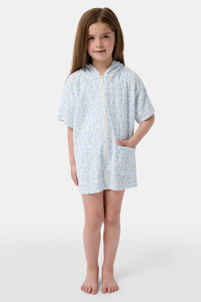 A young child smiles at the camera while wearing the Roller Rabbit Kids Monkey Jesse Cover Up, a white terry zip-up onesie with light blue animal prints and a hood.