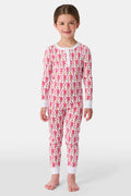A young child smiles in Roller Rabbit Kids Monkey Pajamas—a matching long-sleeve, full-length set made from 100 Pima cotton with a playful monkey pattern and white cuffs, set against a plain white background.