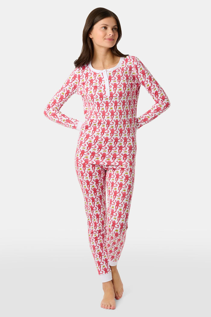 A young child smiles in Roller Rabbit Kids Monkey Pajamas—a matching long-sleeve, full-length set made from 100 Pima cotton with a playful monkey pattern and white cuffs, set against a plain white background.