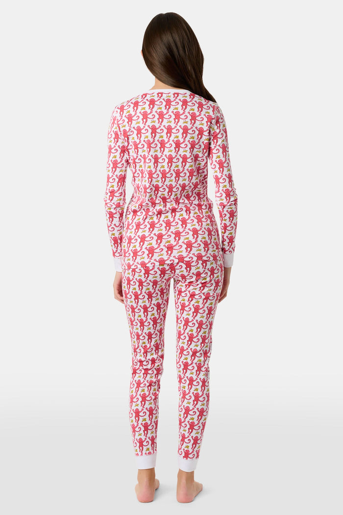 A young child smiles in Roller Rabbit Kids Monkey Pajamas—a matching long-sleeve, full-length set made from 100 Pima cotton with a playful monkey pattern and white cuffs, set against a plain white background.