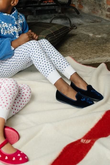A pair of Kids Monkey Verona Slippers by Roller Rabbit, featuring embroidered monkeys, light tan lining, and black soles, is displayed on a plain white background.