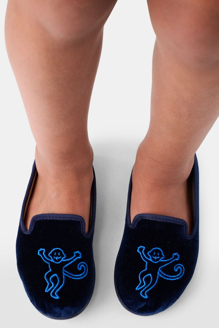 A pair of Kids Monkey Verona Slippers by Roller Rabbit, featuring embroidered monkeys, light tan lining, and black soles, is displayed on a plain white background.