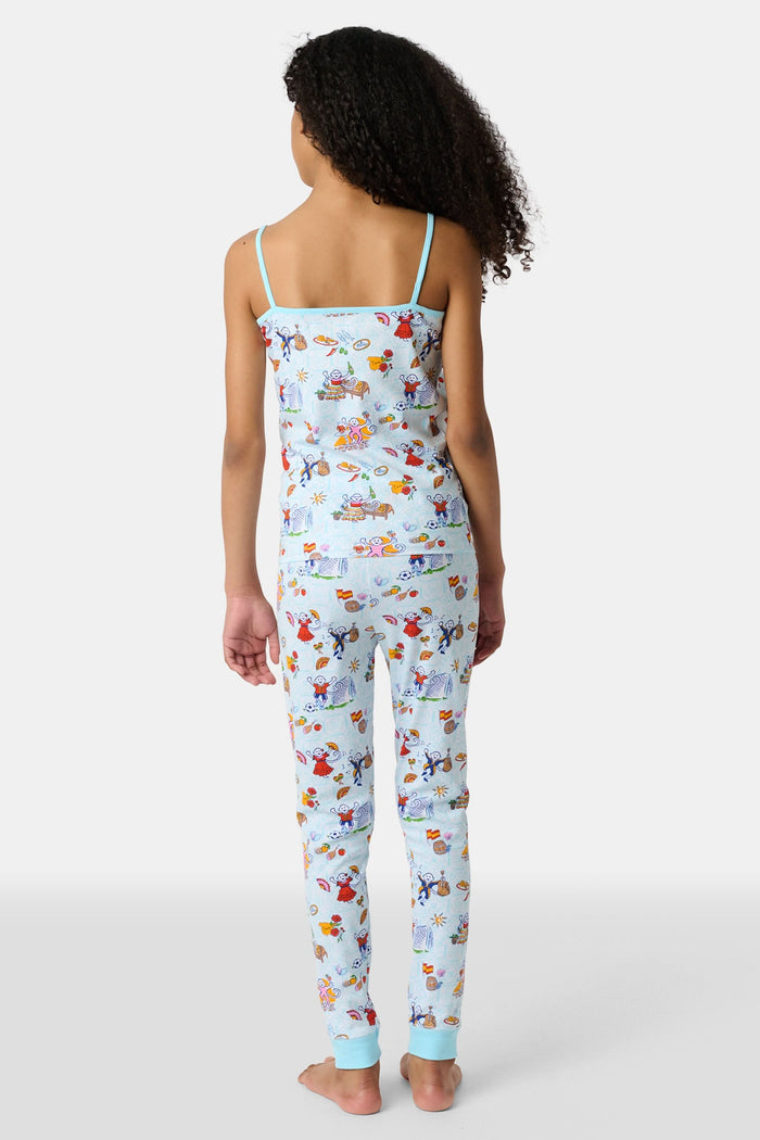 Young child with long brown hair stands barefoot, wearing the Roller Rabbit Kids Spain Monkey Noa Set—light blue Pima cotton loungewear with playful monkey prints and blue trim—against a plain white background.