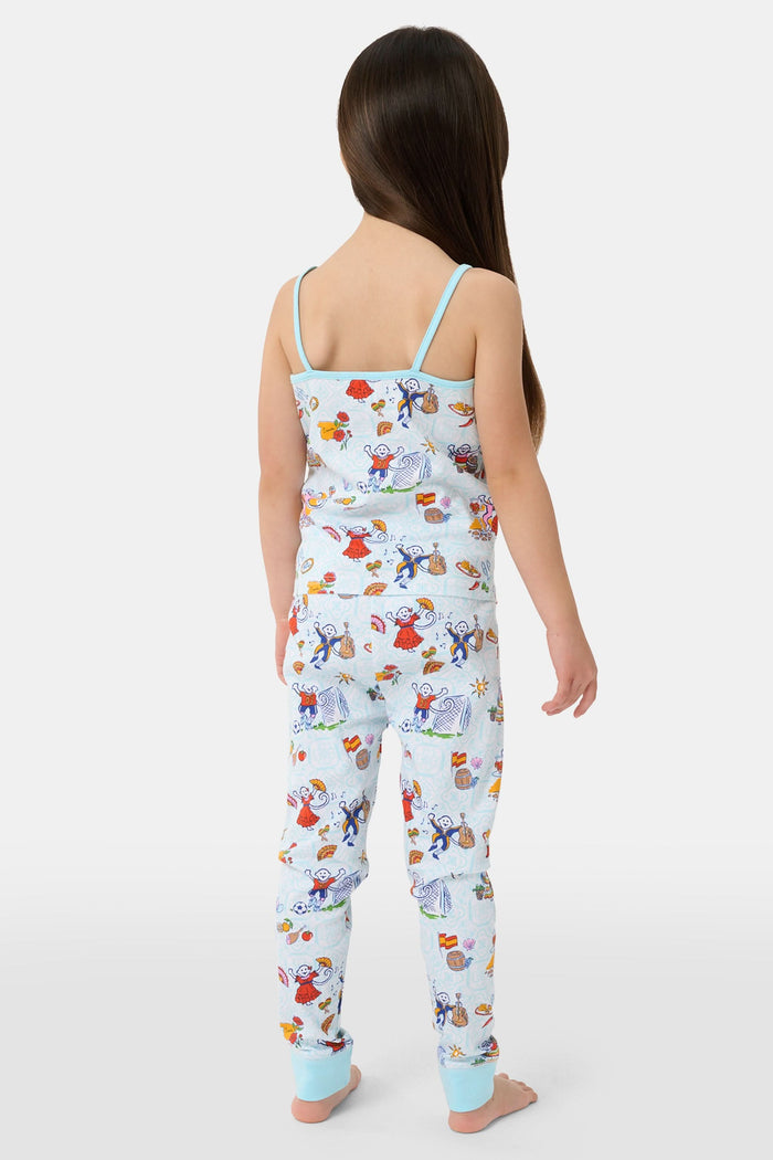 Young child with long brown hair stands barefoot, wearing the Roller Rabbit Kids Spain Monkey Noa Set—light blue Pima cotton loungewear with playful monkey prints and blue trim—against a plain white background.