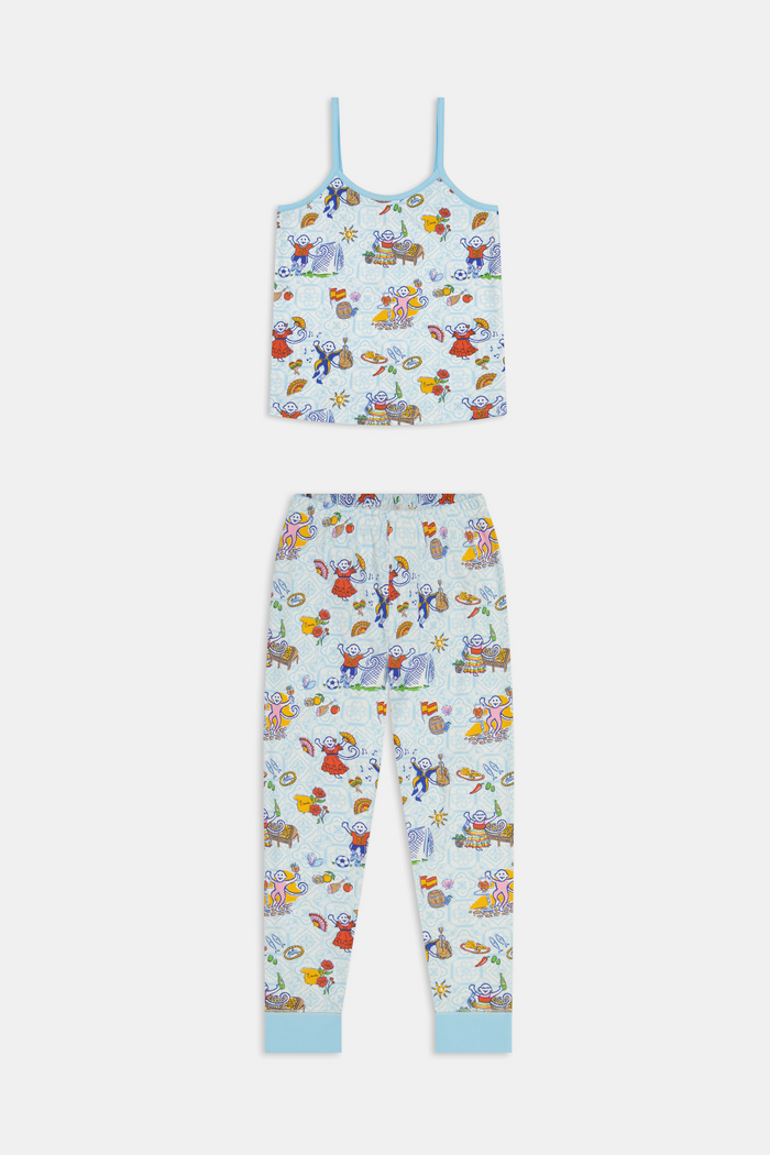 Young child with long brown hair stands barefoot, wearing the Roller Rabbit Kids Spain Monkey Noa Set—light blue Pima cotton loungewear with playful monkey prints and blue trim—against a plain white background.