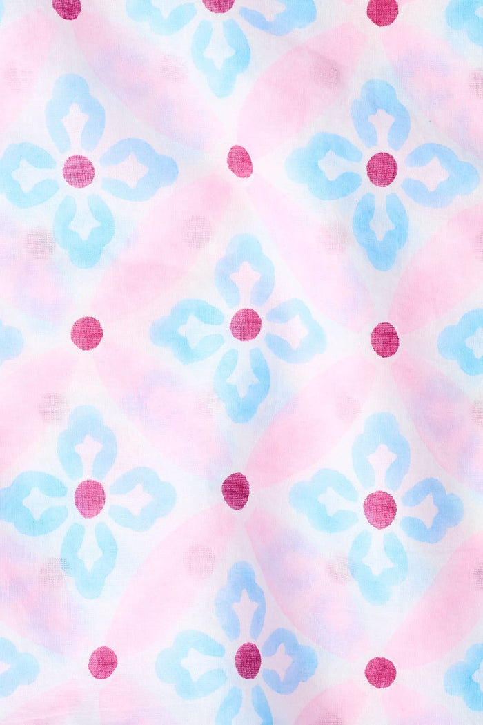 A woman wears the Roller Rabbit Lerato Carmen Jacket, a long-sleeve 100 cotton jacket in light pink with blue and red geometric floral print, white buttons, and two front pockets, standing against a plain white background.