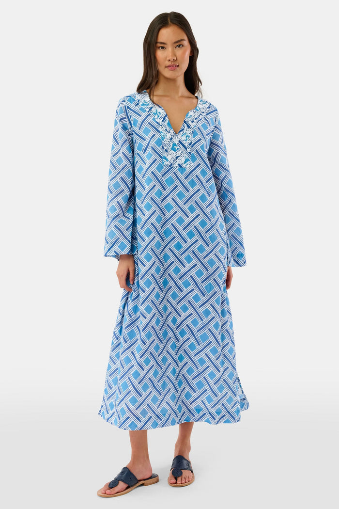 A woman stands in sandals against a white background wearing the Roller Rabbit Liana Astrella Kurta, a blue and white patterned, maxi-length cotton kurta with a V-neck and ruffle detailing.