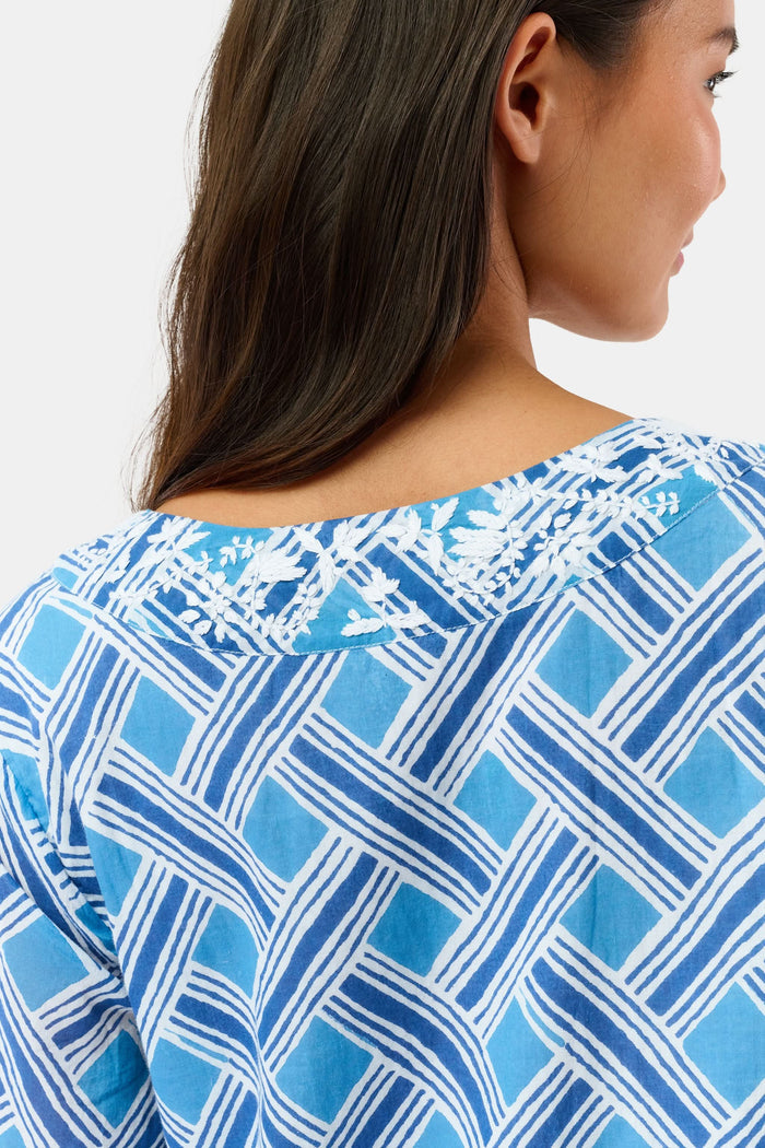 A woman stands in sandals against a white background wearing the Roller Rabbit Liana Astrella Kurta, a blue and white patterned, maxi-length cotton kurta with a V-neck and ruffle detailing.